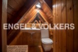 Charming attic bathroom with wooden walls and beams, featuring a sink, toilet, and wicker storage.