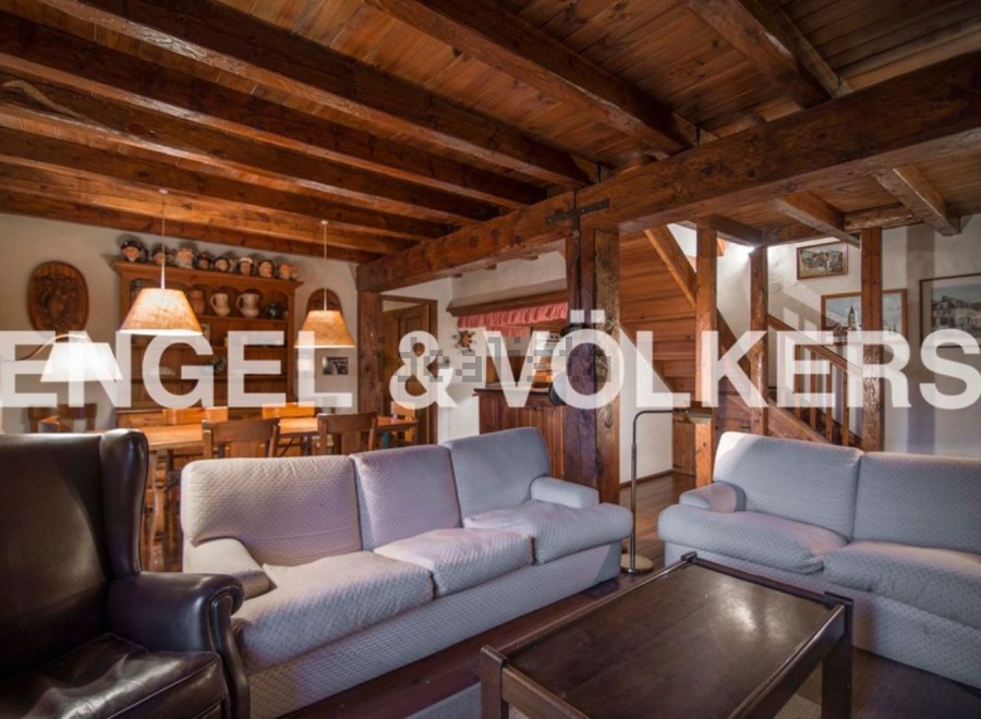 This stunning chalet boasts a spacious living area with exposed wooden beams, creating a warm and inviting atmosphere.
