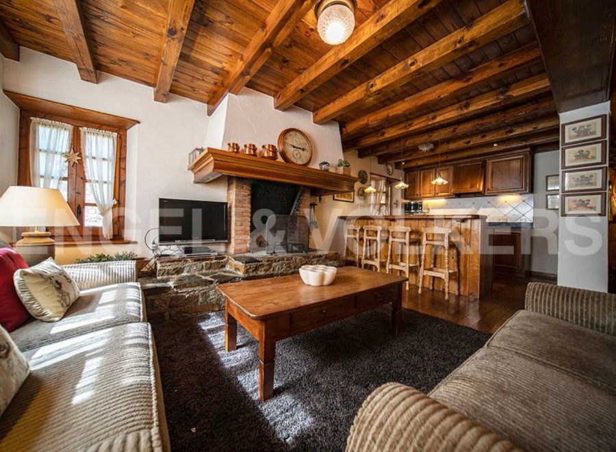Cozy chalet living room with a rustic wooden fireplace and exposed beams.