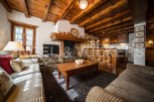 Cozy chalet living room with a rustic wooden fireplace and exposed beams.