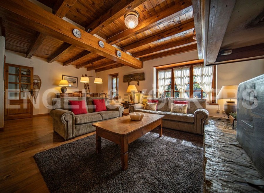 Cozy living room with wooden beams, a fireplace, and comfortable sofas.