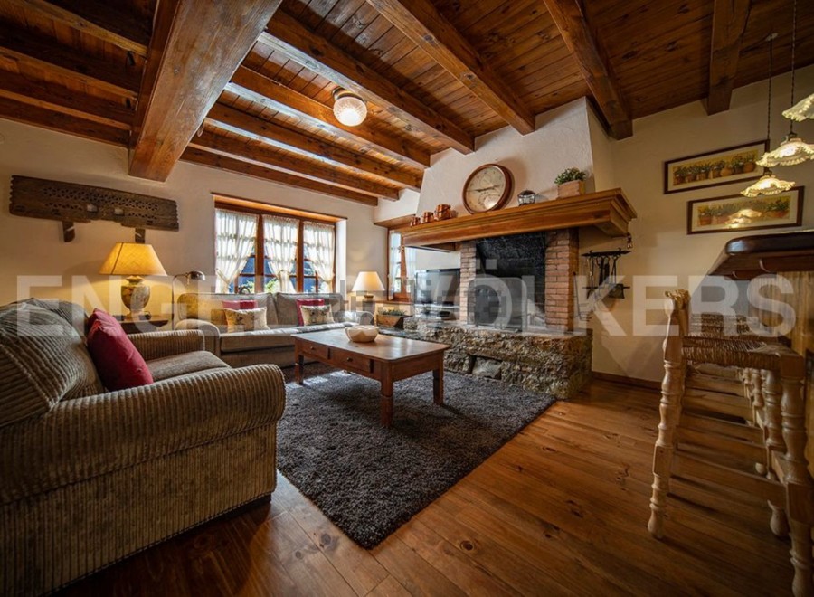 Rustic mountain chalet with exposed wooden beams, a stone fireplace, and hardwood floors.