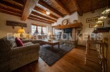Rustic mountain chalet with exposed wooden beams, a stone fireplace, and hardwood floors.