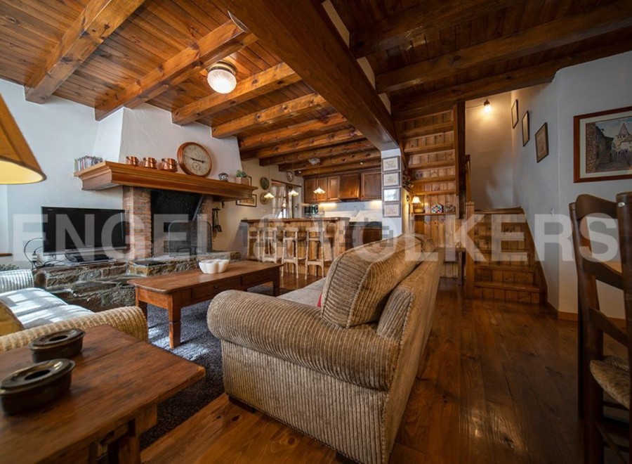 Cozy chalet living room with exposed wooden beams, a stone fireplace, and comfortable corduroy sofa.
