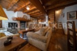 Cozy chalet living room with exposed wooden beams, a stone fireplace, and comfortable corduroy sofa.