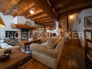 Cozy chalet living room with exposed wooden beams, a stone fireplace, and comfortable corduroy sofa.