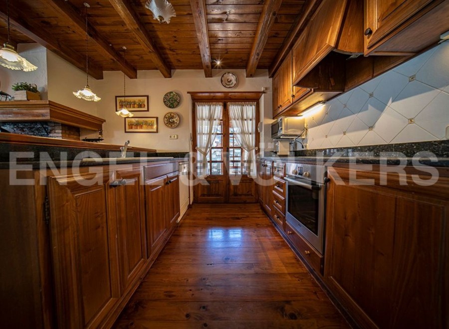 Rustic kitchen with wooden beams, wooden cabinets, and granite countertops.