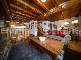 Cozy chalet apartment with exposed wooden beams, a rustic kitchen, and a comfortable living area.