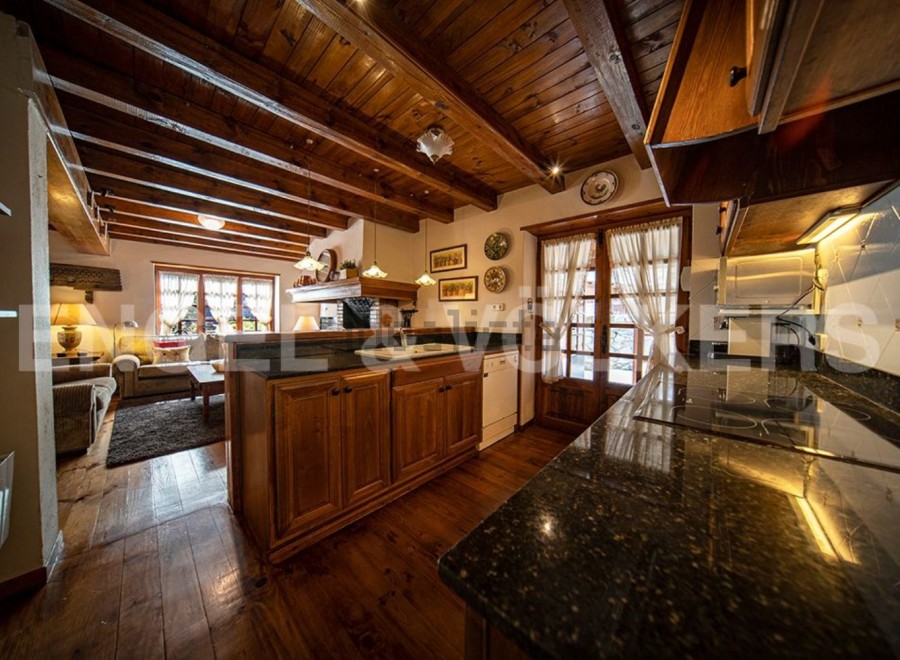This stunning chalet boasts a spacious open-plan living area with exposed wooden beams and a cozy fireplace.