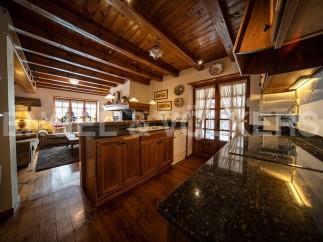 This stunning chalet boasts a spacious open-plan living area with exposed wooden beams and a cozy fireplace.
