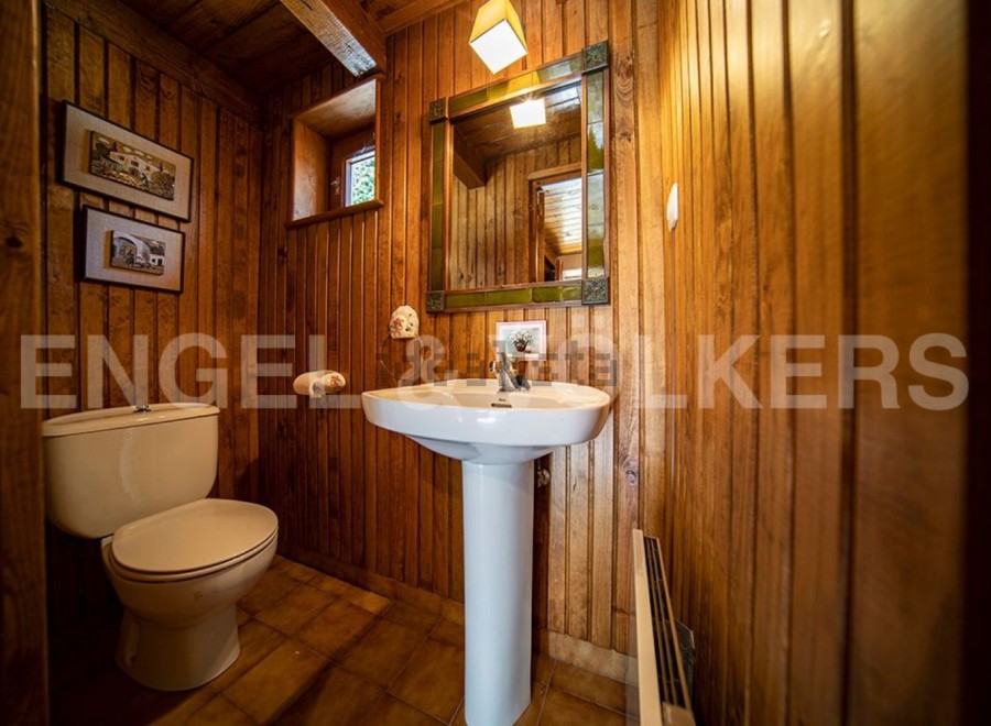 Charming wooden-paneled bathroom with pedestal sink and toilet.