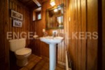 Charming wooden-paneled bathroom with pedestal sink and toilet.