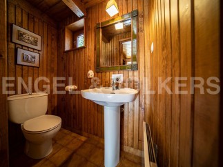 Charming wooden-paneled bathroom with pedestal sink and toilet.