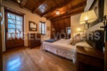 Cozy mountain cabin bedroom with wooden beams, hardwood floors, and a comfortable bed.