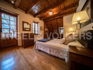 Cozy mountain cabin bedroom with wooden beams, hardwood floors, and a comfortable bed.