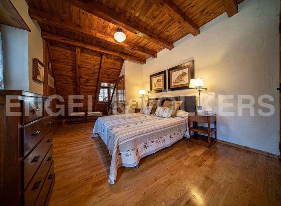 Cozy mountain cabin bedroom with wood-beamed ceiling and hardwood floors.