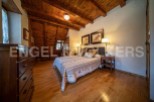 Cozy mountain cabin bedroom with wood-beamed ceiling and hardwood floors.