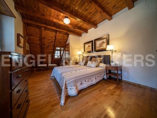 Cozy mountain cabin bedroom with wood-beamed ceiling and hardwood floors.