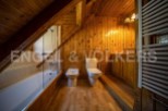 Charming attic bathroom with wooden walls and floors, featuring a bathtub, toilet, and bidet.