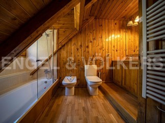 Charming attic bathroom with wooden walls and floors, featuring a bathtub, toilet, and bidet.