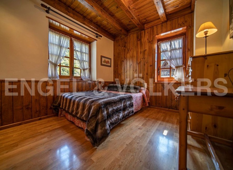Cozy wooden bedroom with two windows offering ample natural light.