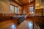 Cozy wooden bedroom with two windows offering ample natural light.