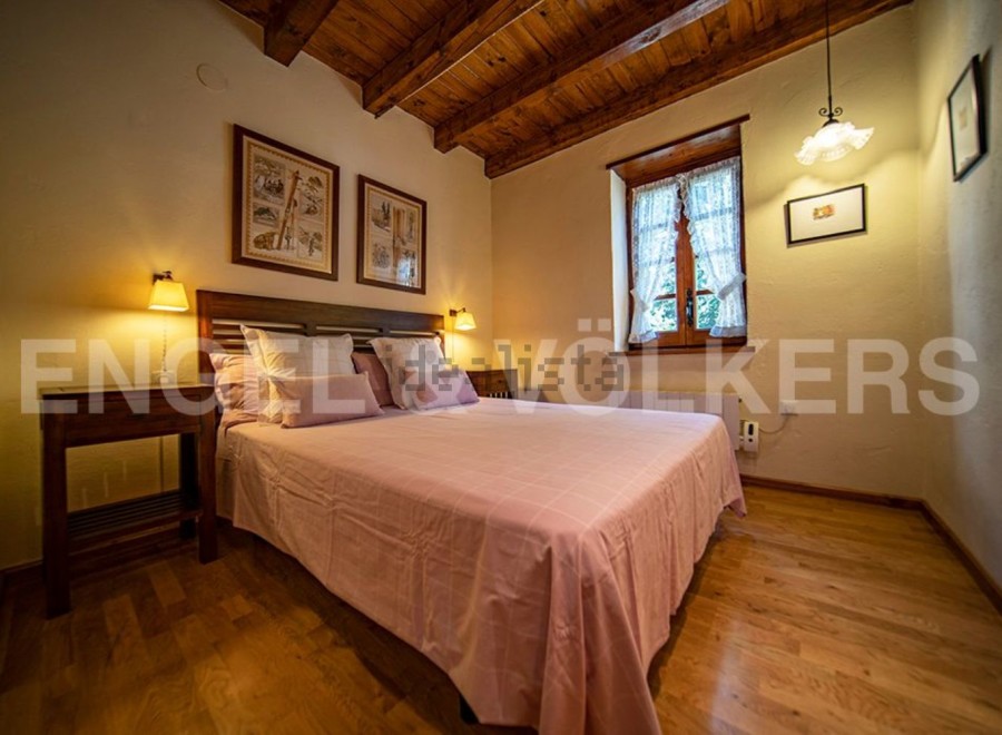 Cozy bedroom with wooden beams and a pink bedspread.