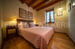 Cozy bedroom with wooden beams and a pink bedspread.