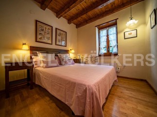 Cozy bedroom with wooden beams and a pink bedspread.