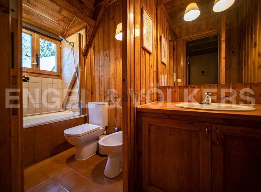 This charming bathroom boasts a rustic wooden design, complete with a bathtub, toilet, and bidet.