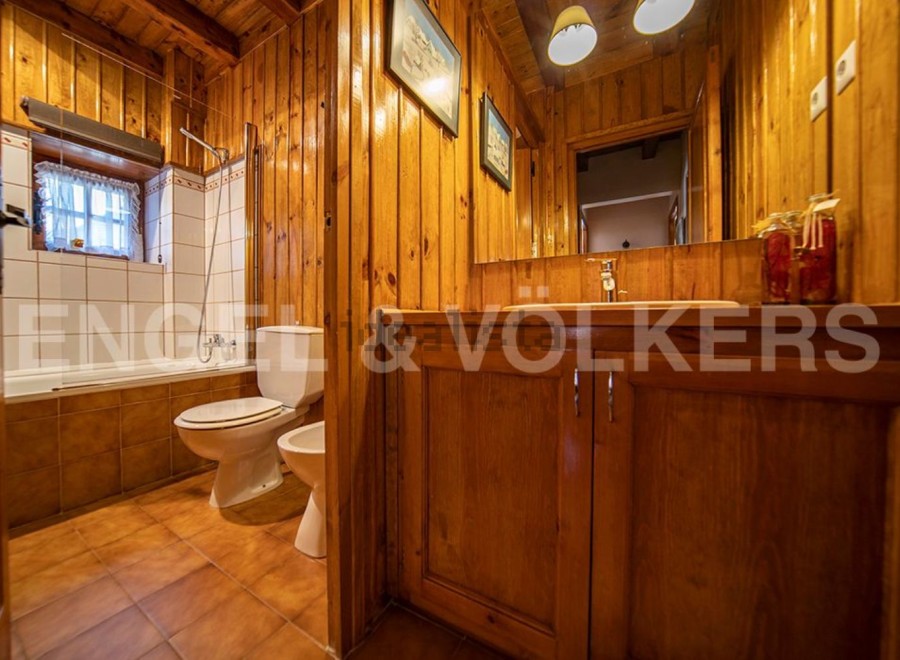 Rustic bathroom with wooden walls and floors, featuring a bathtub, toilet, and bidet.
