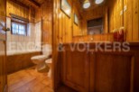 Rustic bathroom with wooden walls and floors, featuring a bathtub, toilet, and bidet.