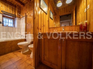 Rustic bathroom with wooden walls and floors, featuring a bathtub, toilet, and bidet.