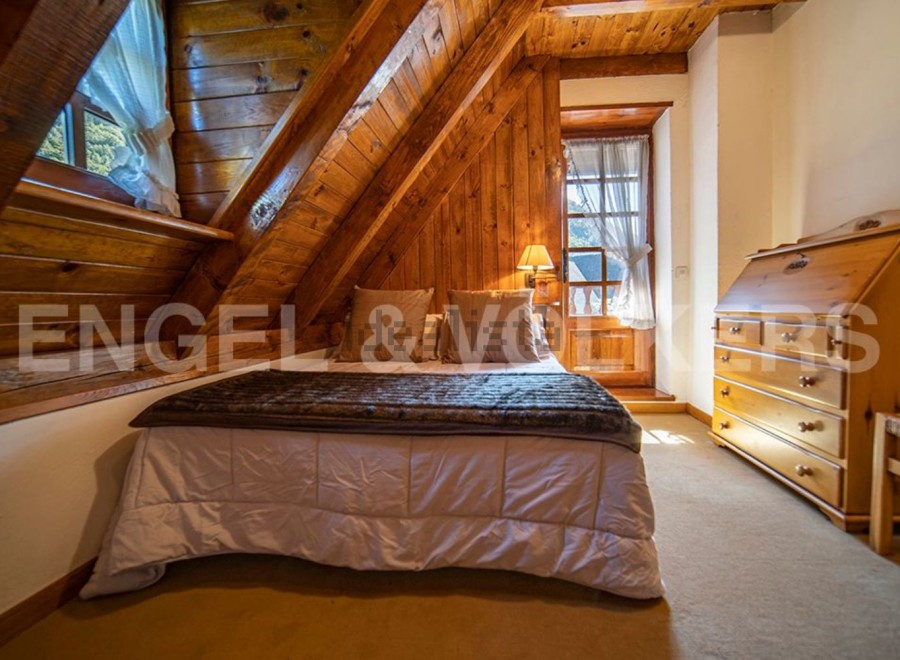 Cozy attic bedroom with wooden beams and a comfortable bed.