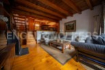 Charming chalet with wooden beams and floors, featuring a cozy living area with a comfortable sofa and a rustic coffee table.