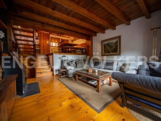 Charming chalet with wooden beams and floors, featuring a cozy living area with a comfortable sofa and a rustic coffee table.