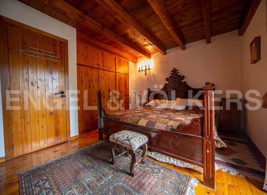 This charming bedroom boasts a rustic wooden bed, wooden floors, and built-in wooden wardrobes.