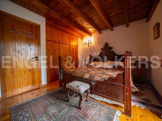 This charming bedroom boasts a rustic wooden bed, wooden floors, and built-in wooden wardrobes.