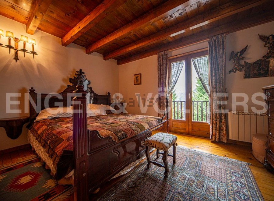 This charming bedroom boasts a rustic wooden bed, antique furniture, and a stunning view from its large windows.