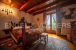 This charming bedroom boasts a rustic wooden bed, antique furniture, and a stunning view from its large windows.