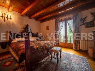 This charming bedroom boasts a rustic wooden bed, antique furniture, and a stunning view from its large windows.