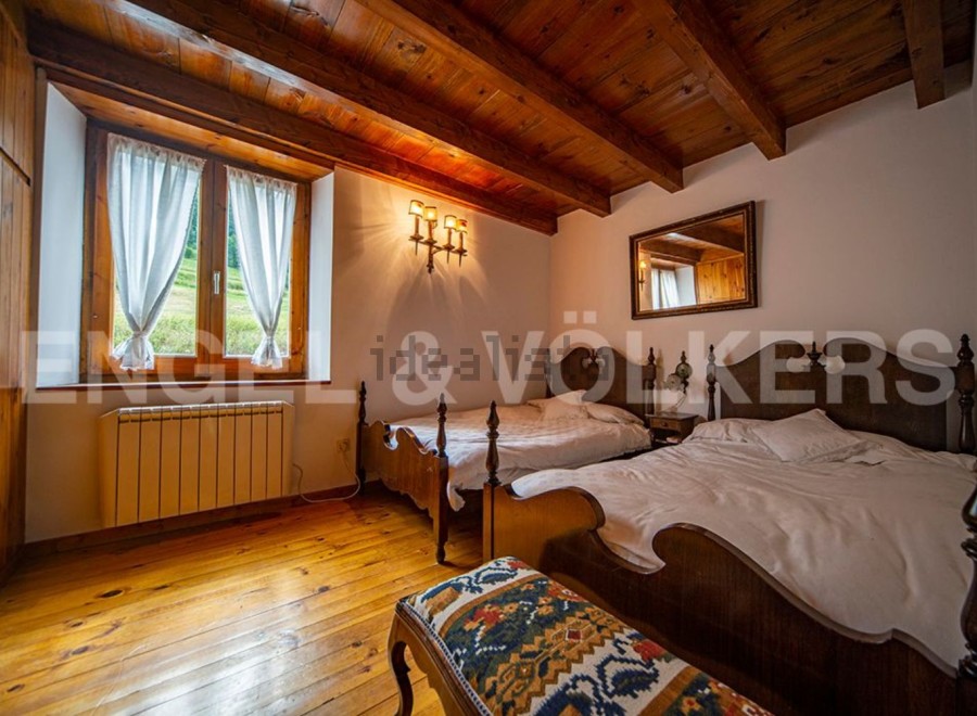 Charming rustic bedroom with wooden beams, twin beds, and a view of the countryside.