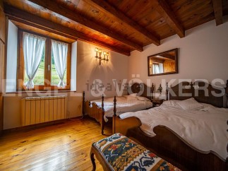 Charming rustic bedroom with wooden beams, twin beds, and a view of the countryside.