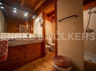 This charming bathroom boasts a rustic wooden vanity with marble countertop, complemented by warm lighting and a spacious mirror.