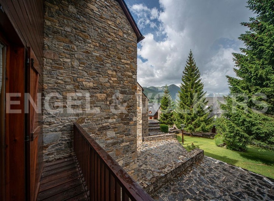 This stunning property boasts a rustic stone exterior and a charming wooden balcony, offering breathtaking mountain views.