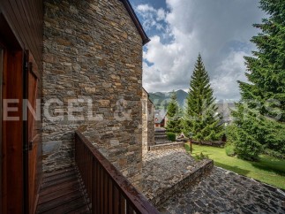 This stunning property boasts a rustic stone exterior and a charming wooden balcony, offering breathtaking mountain views.