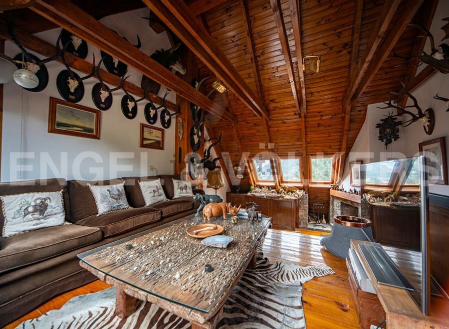 This stunning property boasts a unique, wood-beamed interior with a cozy living area featuring a large sofa and coffee table.