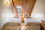 Charming attic bedroom with twin beds, wooden beams, and a skylight offering ample natural light.