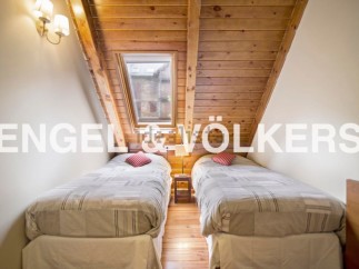 Charming attic bedroom with twin beds, wooden beams, and a skylight offering ample natural light.