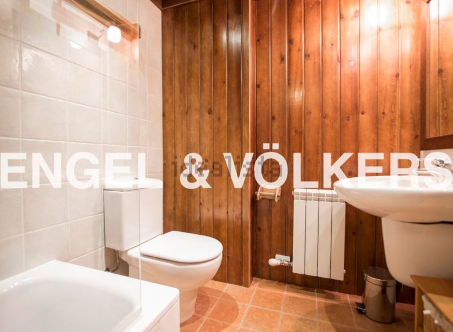 Charming bathroom with wooden wall paneling, white tiled floors, and modern fixtures.